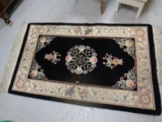 A Chinese fringed rug on black ground