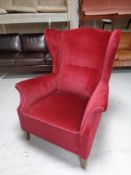 An early 20th century wingback armchair upholstered in a red dralon