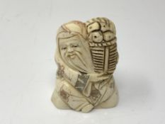 A carved Chinese bone netsuke - Village elder carrying a basket of food