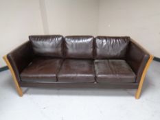 A Scandinavian wood framed three seater settee upholstered in a brown leather