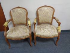 A pair of carved beech framed salon armchairs upholstered in a gold floral fabric