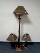 A wooden standard lamp with leather effect shade together with matching pair of table lamps