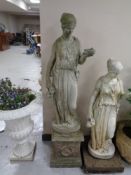 A concrete garden statue of a maiden on plinth