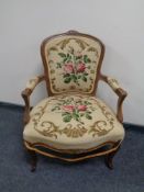A carved beech framed French salon armchair upholstered in a tapestry fabric