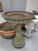 A concrete classical garden bird bath together with two further plant pots