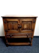 An oak linen fold double door cabinet on raised legs