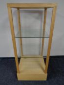 A square oak shop display stand with three glass shelves
