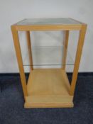 A square oak shop display stand with two glass shelves