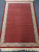 A fringed Persian design rug on red ground,