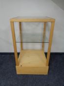 A square oak shop display stand with two glass shelves