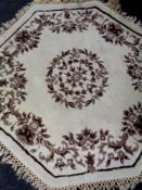 A hexagonal floral fringed rug on cream ground.