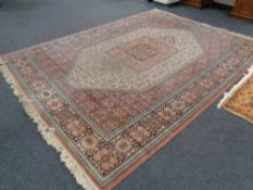 A machine made Persian design fringed carpet on pink ground,