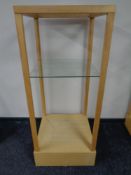 A square oak shop display stand with two glass shelves