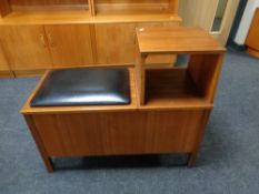 A 20th century teak storage telephone table with black vinyl seat