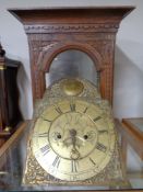 A 19th century carved oak longcase clock hood with movement and brass face,