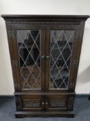 A double leaded glass door bookcase fitted cupboards below in an oak finish