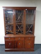 A Regency style triple door glazed bookcase fitted cupboards and drawers beneath with lion mask