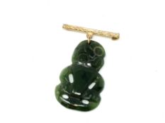 A Maori jade tiki suspended on 9ct gold bar brooch