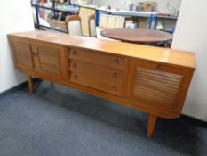 A mid 20th century teak triple door triple drawer sideboard on raised legs,