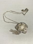 A decorative filigree style silver pendant on chain