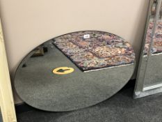 A frameless oval mirror,