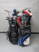 Four golf bags containing a quantity of assorted irons,