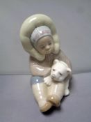 A Lladro figure - seated Eskimo boy with polar bear cub