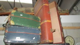 Two vintage suitcases and a large travel trunk.