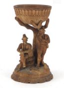 C19th Black Forest carved wooden bowl on figural stand depicting two peasants beneath a tree,