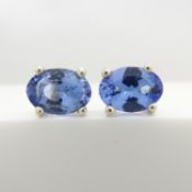 A pair of silver ear studs set with oval-cut tanzanite gemstones, boxed