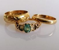Two gold wedding bands, one with etched decoration and a gem-set ring (two stones missing), all