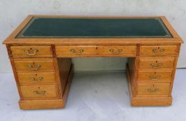 A Georgian-style light oak twin pedestal desk with tooled leather inset over an arrangement of