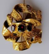 A Victorian gold ribbon-knot brooch with garnet decoration, not marked but tests for high quality