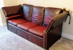 A vintage Knole three-seat drop arm sofa upholstered in red studded leather, 102 h x 230 w x 90 d