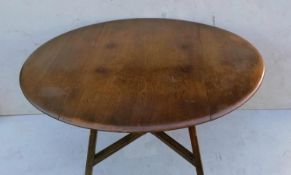An Ercol beech and elm drop leaf table with X-shape stretcher, blue label, 72 cm H, 113 cm diameter,