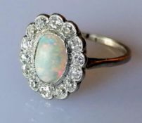 An oval opal (9mm x 6mm) cluster ring with 14 round brilliant-cut diamonds, total approximate