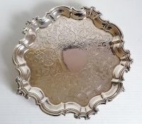 A Victorian silver salver with etched decoration and pie crust border on three claw and ball feet by