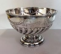A late Victorian silver punch bowl with embossed swag and half-flute decoration on a stepped foot,