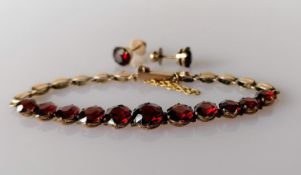 A garnet and gold bracelet with matching earrings, unmarked, the eleven garnets range from 0.5-1.0
