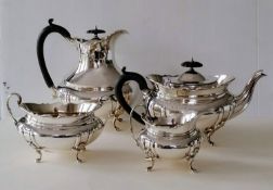 A George V four-piece matching silver tea service of oval bombe form, ebonized fruitwood handles,