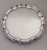 An Edwardian silver salver with pie-crust rim on four scroll feet by James Dixon & Sons Ltd.,