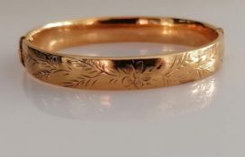 A 9ct yellow gold bangle with etched decoration, 62mm x 58mm, hallmarked for Birmingham, 1970, clasp
