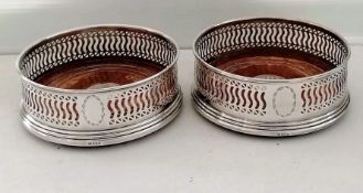 A pair of silver bottle coasters with pierced decoration, vacant cartouches, on stepped bases by W I
