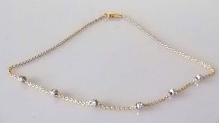 A gold and diamond necklace with six diamond-set rondels, each set with six round brilliant-cut diam