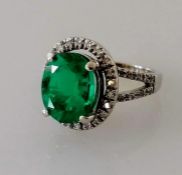 An oval emerald and diamond cluster ring, 10 x 7.9 5.35mm weighing a calculated 2.50 carats, vivid g