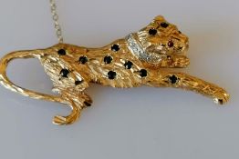 A Cartier-style 9ct yellow gold leopard brooch with ruby eye, stud diamond collar and sapphire decor