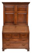 An 18th Century oak bureau cabinet:, the upper part with a moulded dentil cornice,