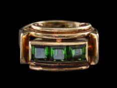 A 1940s green tourmaline ring,: set with three square cut green tourmaline, between scrolled sides,