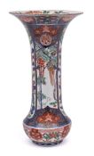 A Japanese Imari sleeve vase: painted with underglaze blue bordered panels of peony,