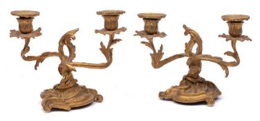 A pair of gilt metal twin-branch candlesticks in Louis XV style: with urn shaped sconces on swept